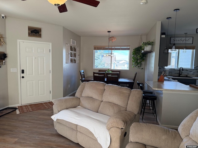 living room featuring plenty of natural light, wood finished floors, a ceiling fan, and baseboards