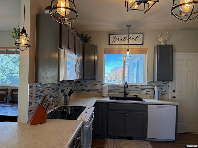 kitchen featuring white appliances, decorative backsplash, a sink, and light countertops