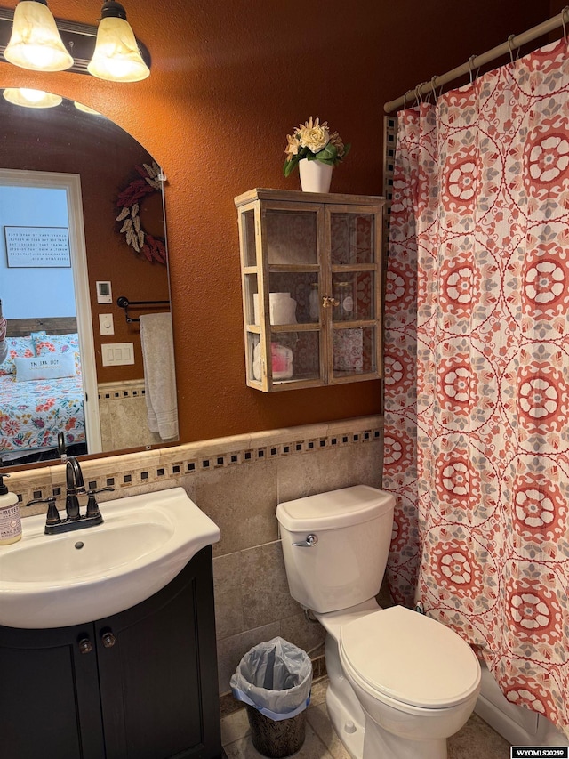 bathroom with curtained shower, tile walls, vanity, and toilet