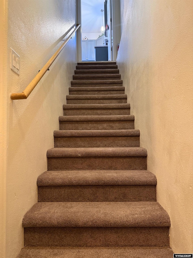 staircase featuring a textured wall