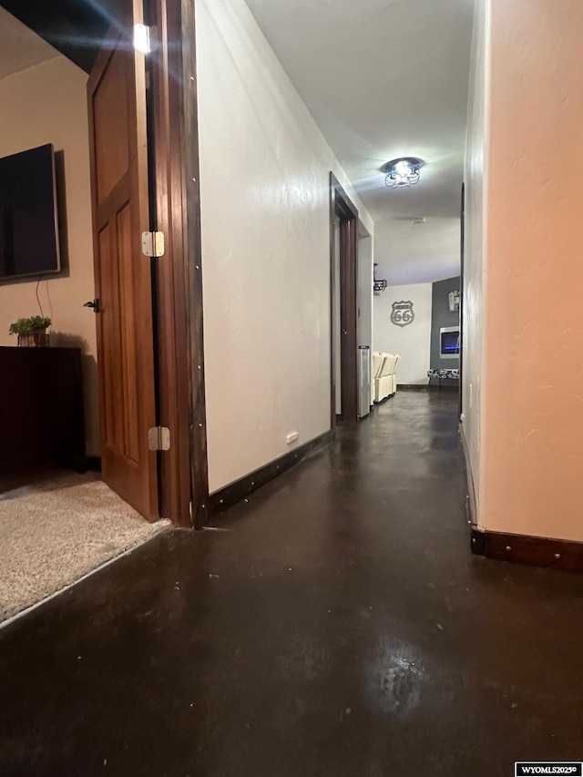 corridor featuring concrete floors and baseboards