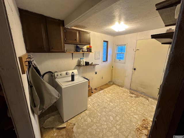 clothes washing area featuring cabinet space, washer / clothes dryer, and a textured ceiling