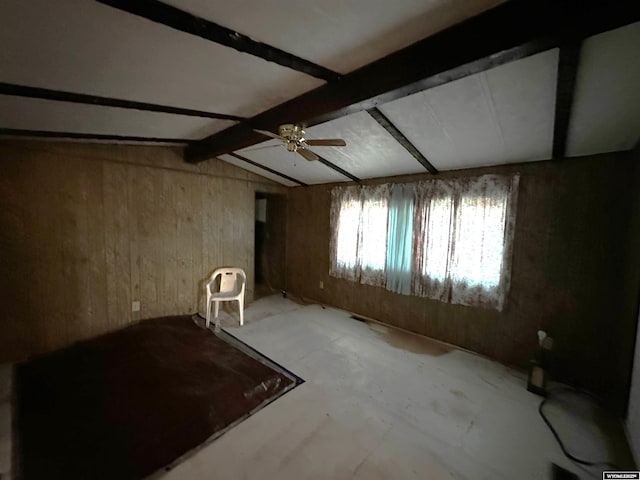 interior space featuring a ceiling fan, wood walls, and lofted ceiling with beams