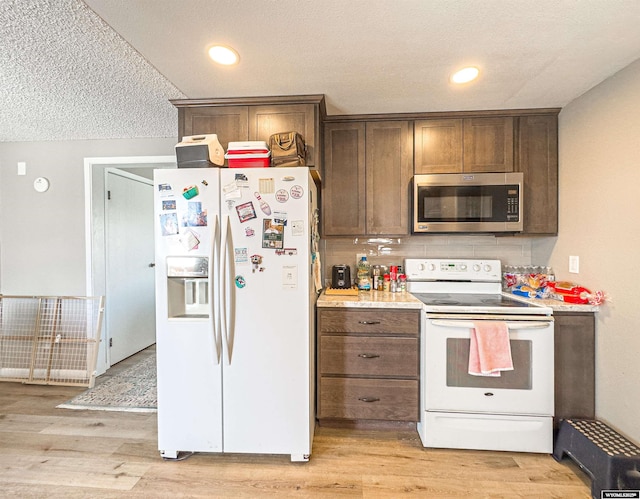 kitchen featuring tasteful backsplash, white appliances, light countertops, and light wood-type flooring