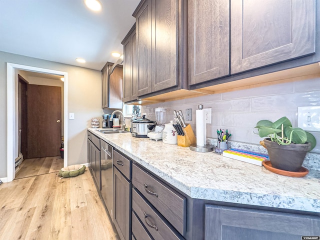 kitchen with light countertops, light wood-type flooring, backsplash, and a sink