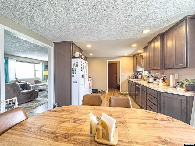 dining room with recessed lighting, light wood-type flooring, and a textured ceiling