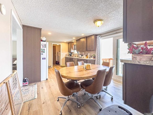 dining room featuring light wood finished floors, recessed lighting, and a textured ceiling