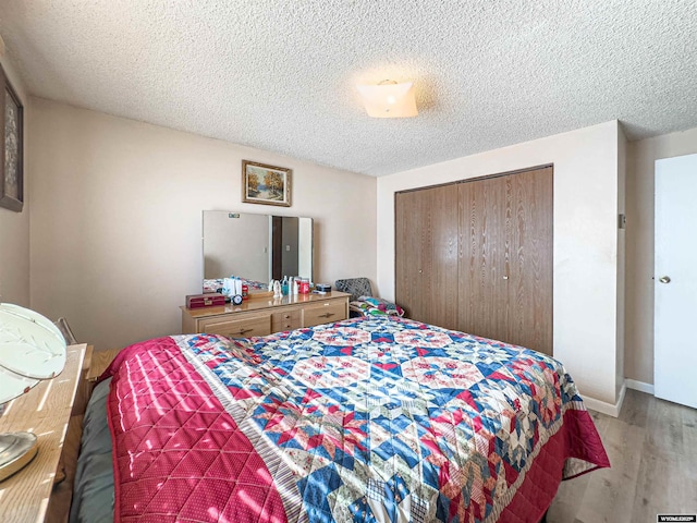 bedroom featuring a closet, a textured ceiling, and light wood-style floors