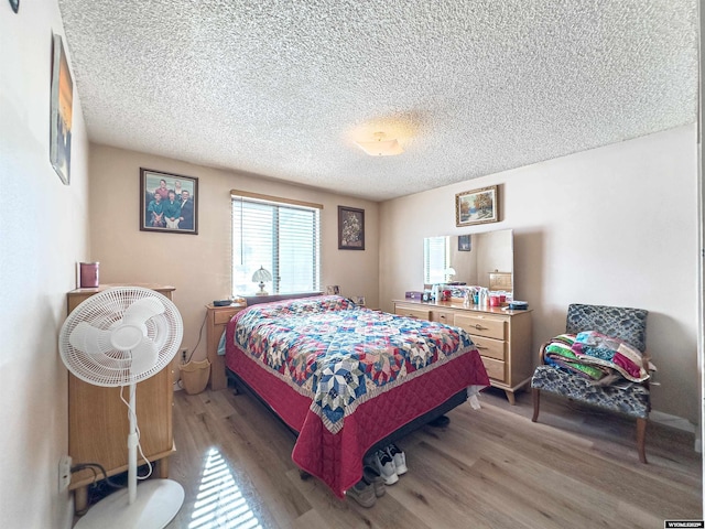 bedroom with light wood-style floors and a textured ceiling