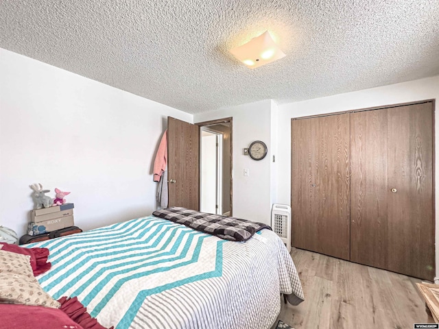 bedroom featuring light wood-type flooring, a closet, and a textured ceiling