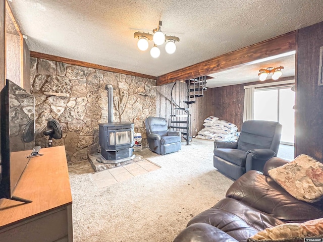 living area with stairs, carpet floors, beam ceiling, a wood stove, and a textured ceiling