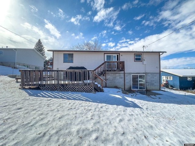 snow covered rear of property with a deck