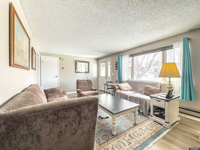 living room with a textured ceiling, light wood-style floors, and a baseboard radiator