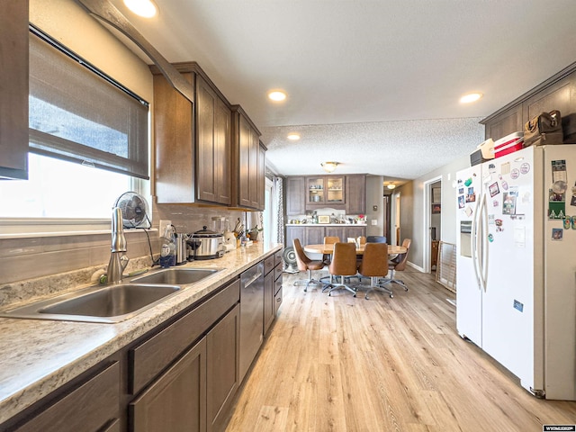 kitchen with a sink, light countertops, white refrigerator with ice dispenser, light wood-style floors, and dishwasher