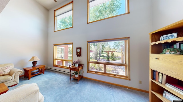 sitting room featuring carpet, baseboards, a high ceiling, and baseboard heating