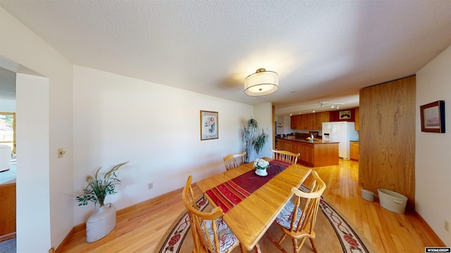 dining area with a textured ceiling and light wood-style flooring