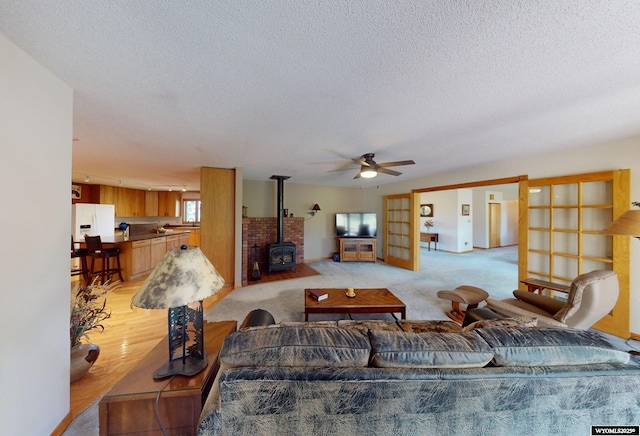 living area featuring a wood stove, ceiling fan, a textured ceiling, and french doors