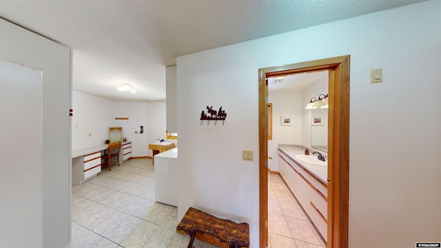 corridor featuring a sink, light tile patterned floors, a textured ceiling, and washer / dryer