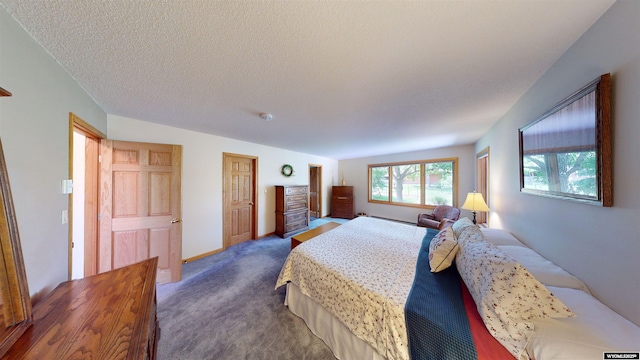 bedroom featuring dark carpet, a textured ceiling, and baseboards