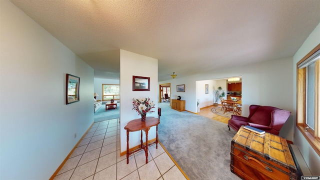 living area featuring light tile patterned flooring, a textured ceiling, and baseboards