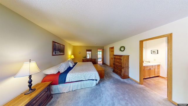 bedroom featuring light carpet, a textured ceiling, and ensuite bathroom