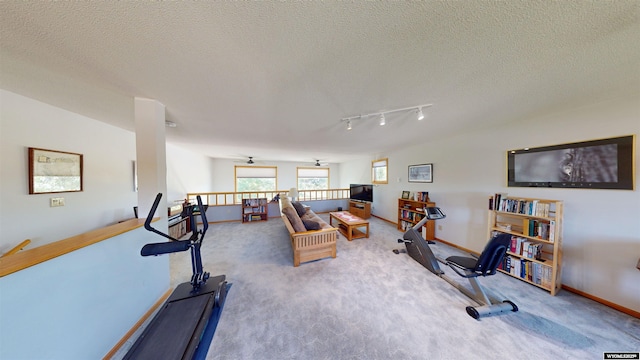 exercise area with a textured ceiling, ceiling fan, carpet, and baseboards