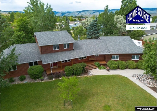 view of front of home featuring a shingled roof, a front yard, and a mountain view