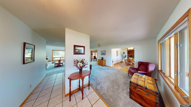 living area with light carpet, a textured ceiling, baseboards, and light tile patterned floors