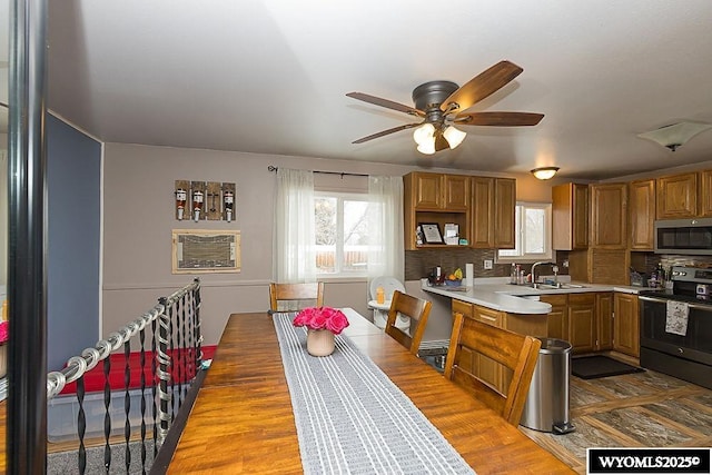 kitchen featuring light countertops, stainless steel microwave, electric range, decorative backsplash, and brown cabinetry