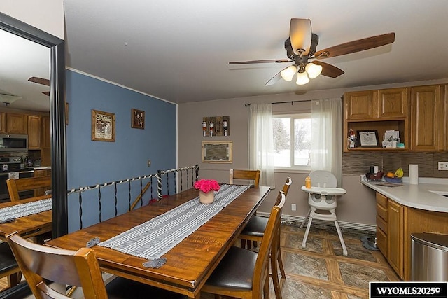 dining space featuring ceiling fan and baseboards