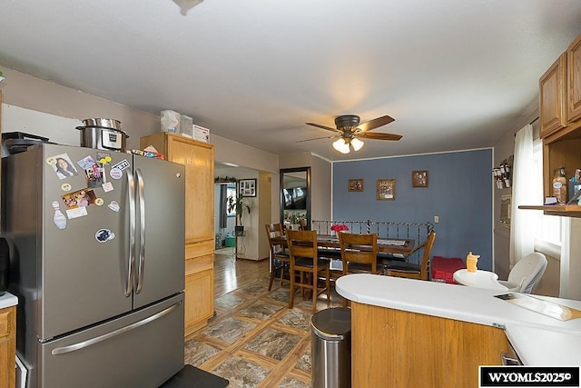 kitchen with ceiling fan, light countertops, freestanding refrigerator, and brown cabinets