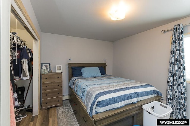 bedroom featuring a closet, baseboard heating, and wood finished floors