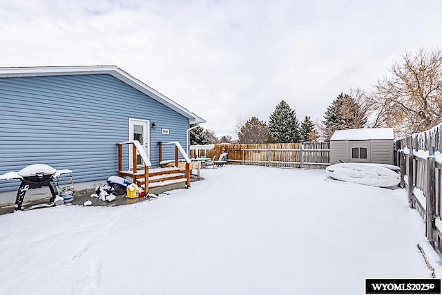 yard covered in snow featuring a storage shed, a fenced backyard, and an outdoor structure