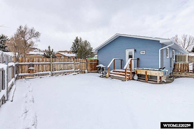 snow covered house featuring a fenced backyard