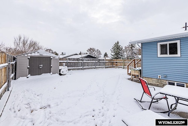 yard covered in snow featuring an outbuilding, a shed, and a fenced backyard