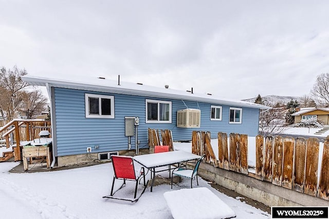 snow covered back of property featuring outdoor dining area and fence