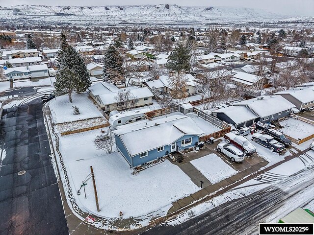 snowy aerial view featuring a residential view and a mountain view