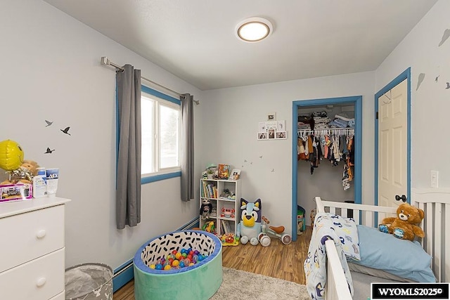 bedroom featuring a closet, baseboard heating, and wood finished floors