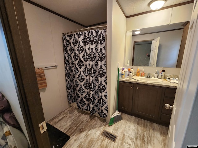 bathroom featuring crown molding, visible vents, a textured ceiling, vanity, and wood finished floors