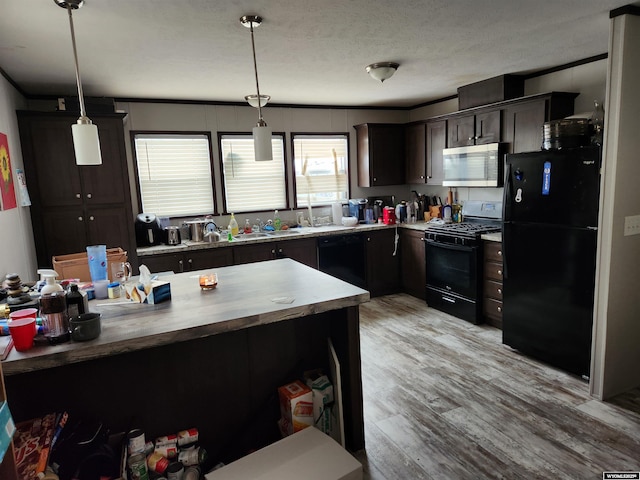 kitchen featuring black appliances, light wood-style flooring, pendant lighting, and a textured ceiling