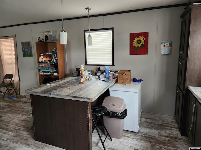 kitchen featuring a breakfast bar area, light countertops, wood finished floors, and decorative light fixtures