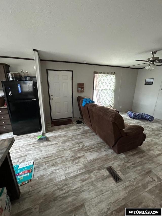 living room featuring a textured ceiling, wood finished floors, visible vents, and a ceiling fan