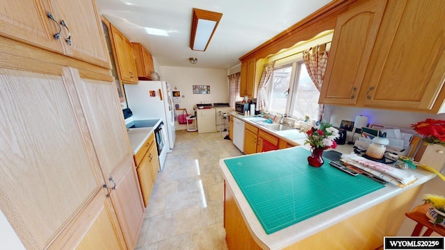 kitchen with independent washer and dryer, white appliances, light countertops, and a sink