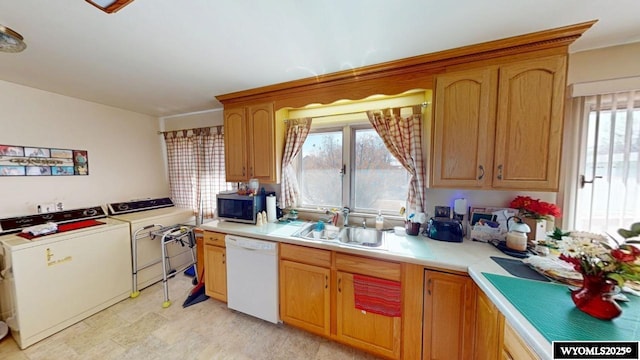 kitchen featuring a sink, stainless steel microwave, separate washer and dryer, white dishwasher, and light countertops