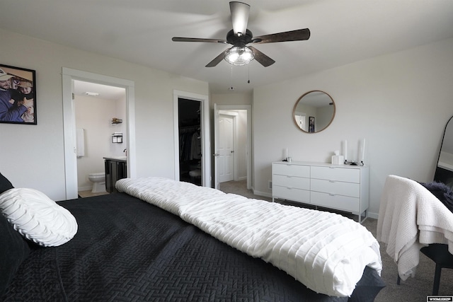 bedroom featuring baseboards, ensuite bath, ceiling fan, a spacious closet, and a closet