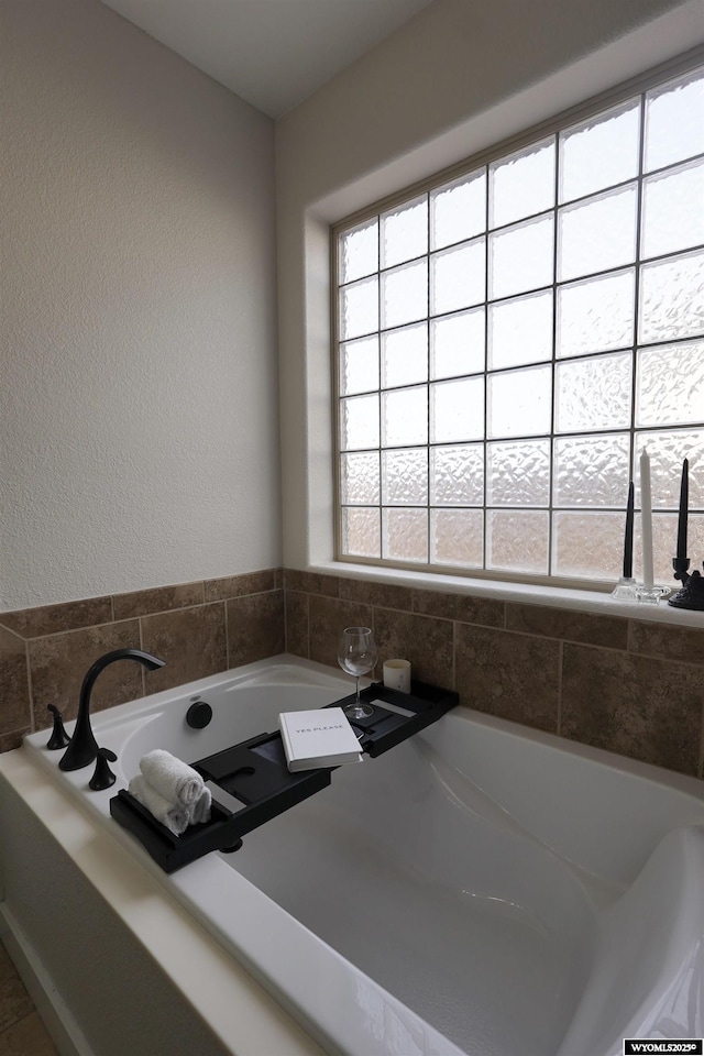 bathroom with a bath and a textured wall