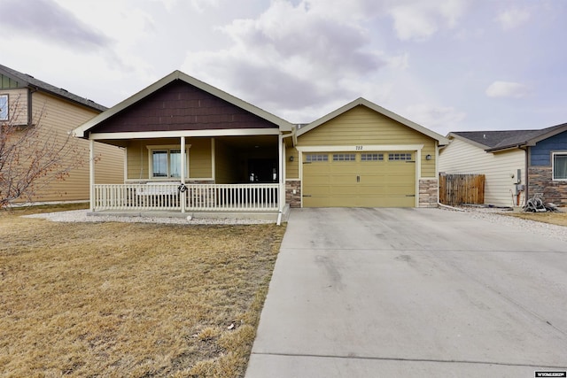 view of front of property featuring a porch, stone siding, driveway, and a garage