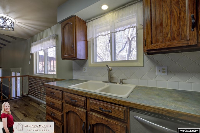 kitchen with decorative backsplash, dark countertops, a sink, and stainless steel dishwasher