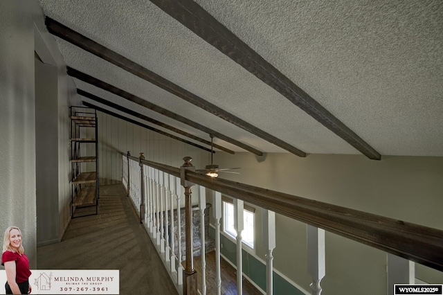 hallway with vaulted ceiling with beams and a textured ceiling