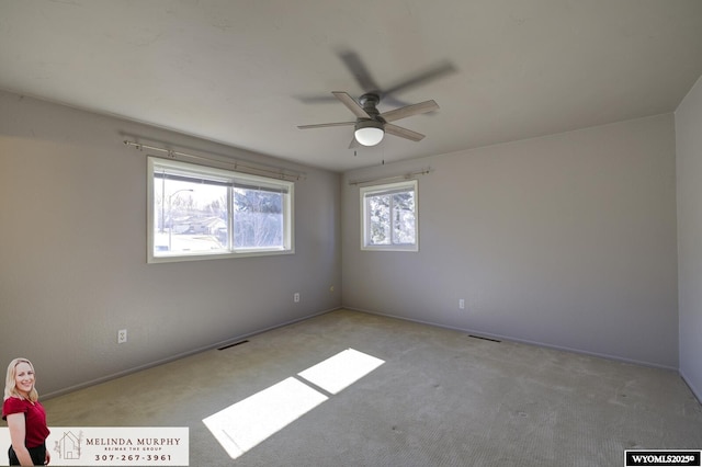 empty room featuring carpet floors, baseboards, visible vents, and ceiling fan